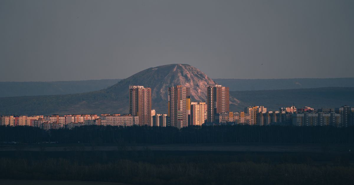 A stunning cityscape of Ufa at dusk showcasing high-rise buildings and a mountain backdrop.