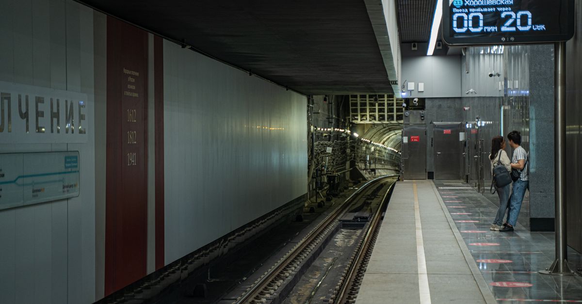 A couple stands on a subway platform, anticipating the next train arrival in Moscow's metro.