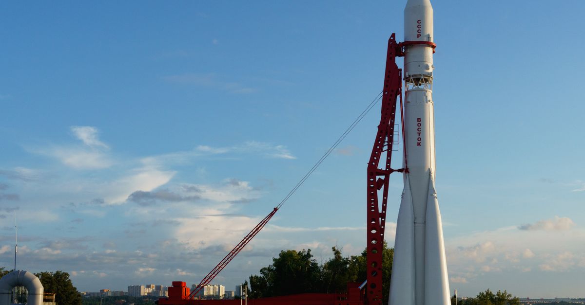 Vostok rocket stands poised on launch pad under clear blue sky at space center.