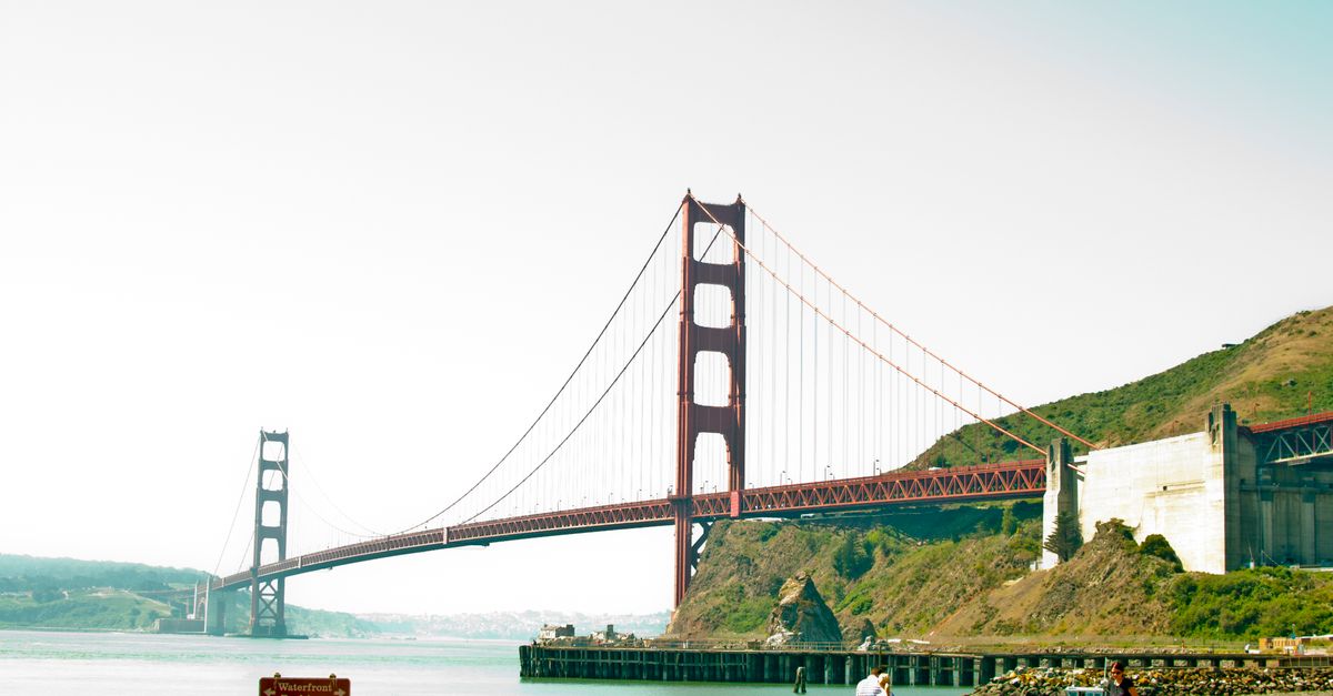 Scenic view of the Golden Gate Bridge with people in foreground on a sunny day.