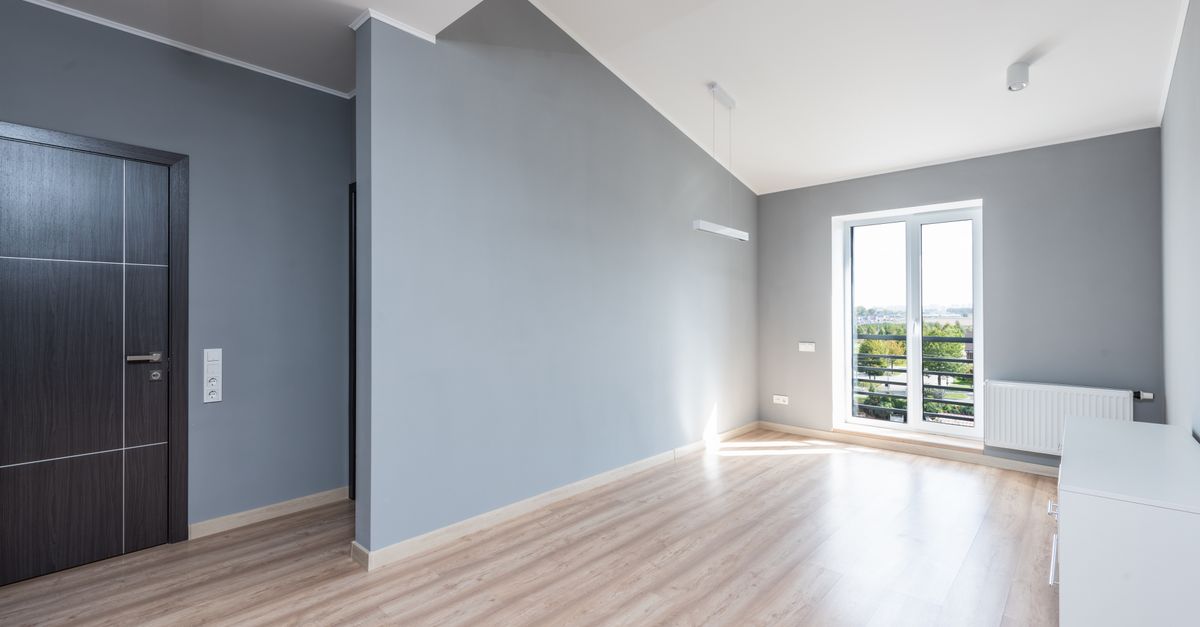 Bright, spacious minimalist room with wooden flooring and large window view.