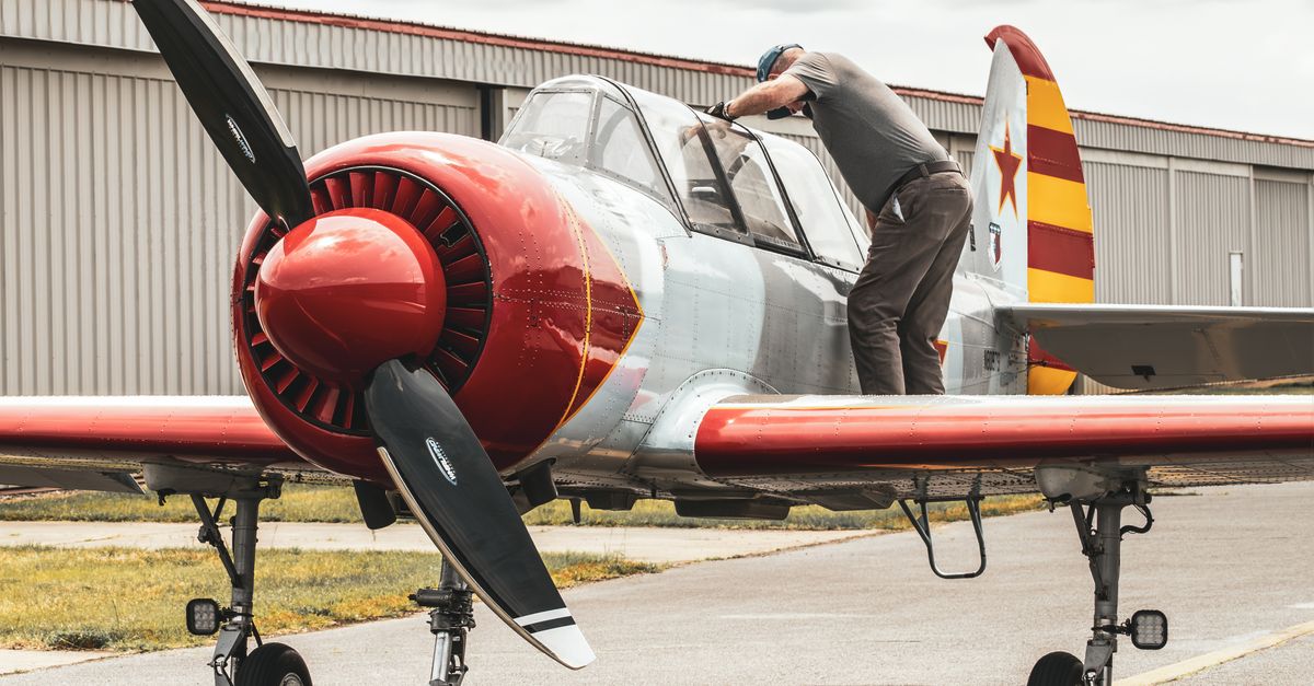 A pilot examining a Yakovlev Yak-52 aircraft on the tarmac in Raleigh, NC.