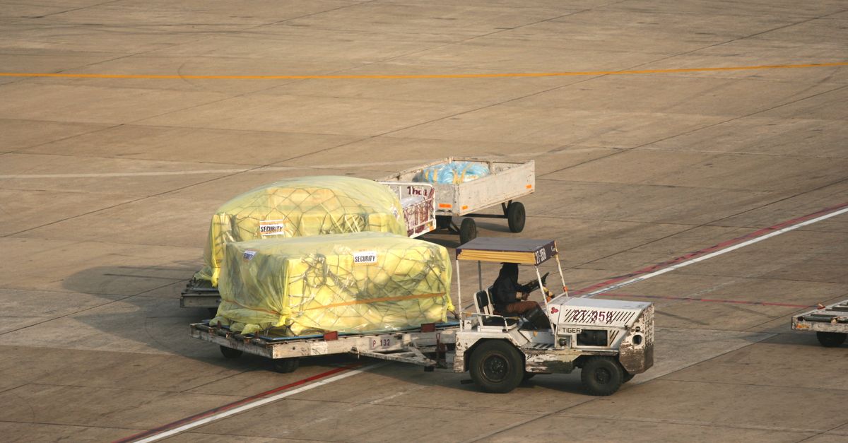 Cargo being handled on the tarmac at Bangkok Airport. Seen from above, this includes trailers and ground staff.