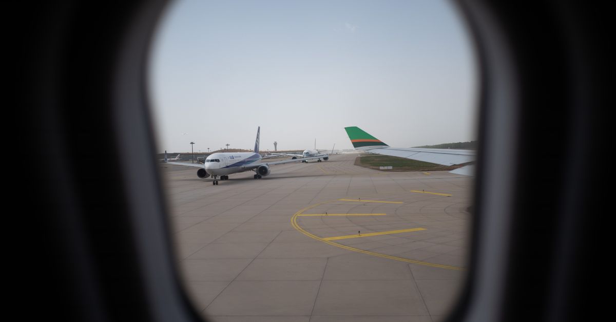 Airplane seen through a window, parked on the airport runway, capturing a travel moment.