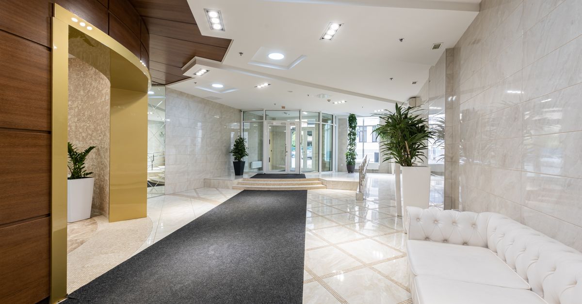 Interior of contemporary spacious lobby without people with white leather sofa and long black carpet