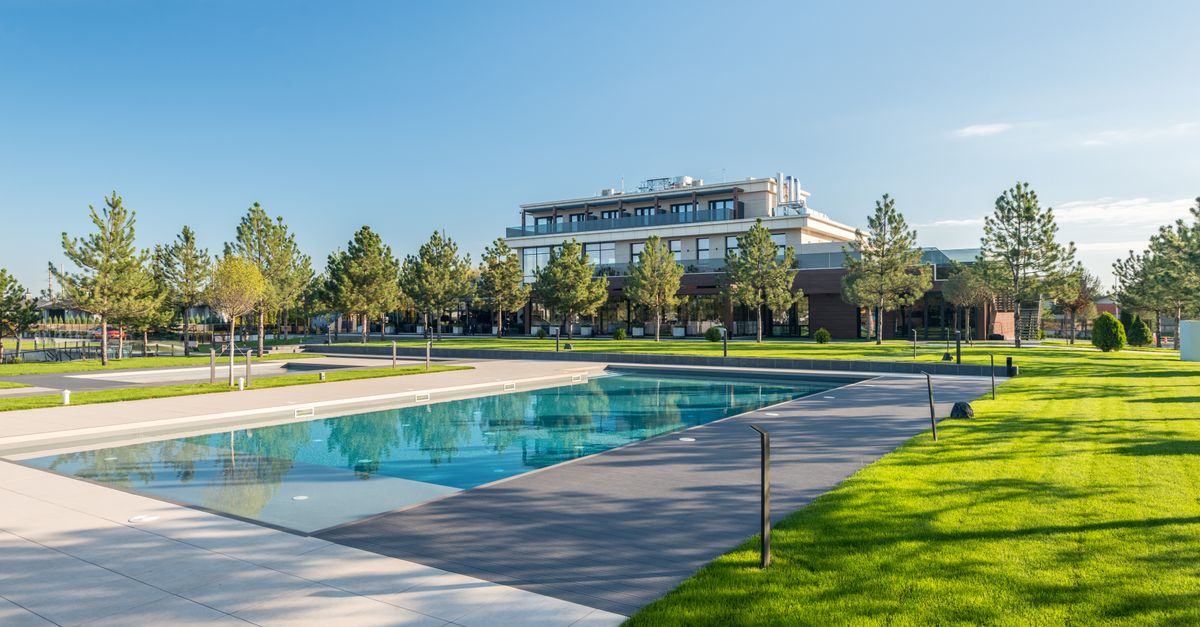 Elegant poolside at a modern resort with lush greenery and clear blue skies, ideal for luxury travel.