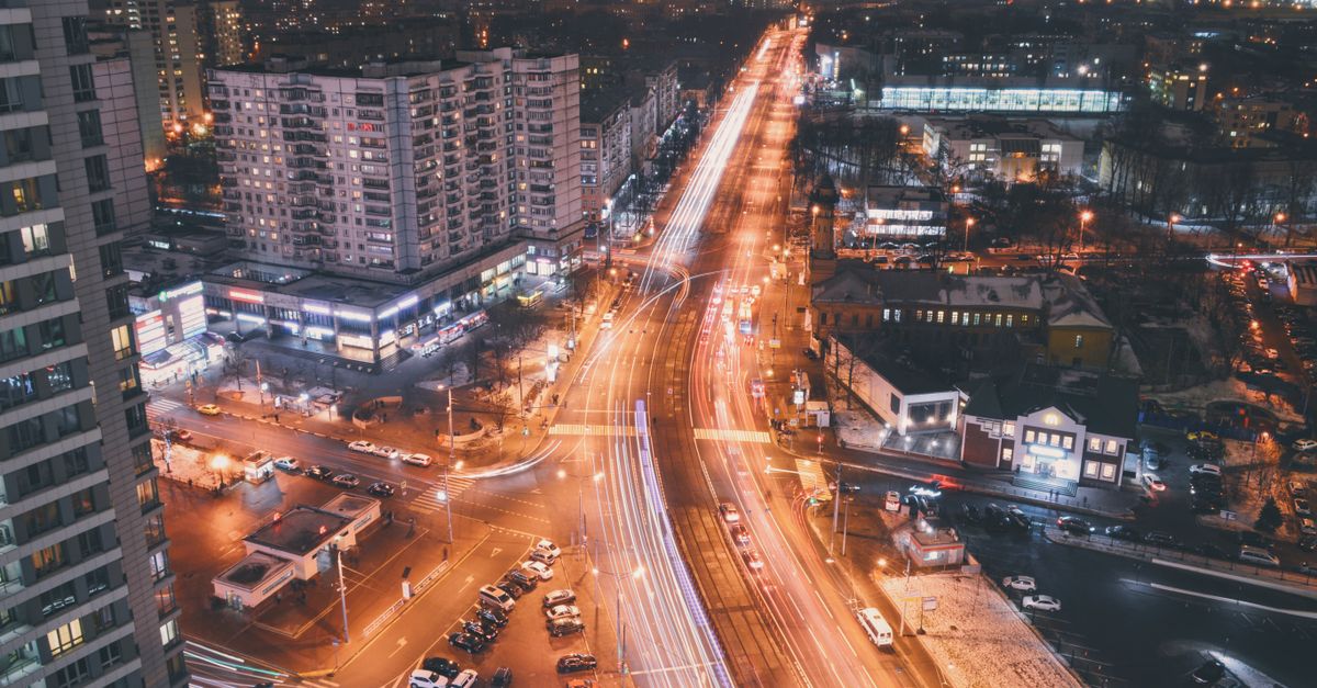 Dynamic aerial view of city streets at night with vibrant light trails and skyscrapers.