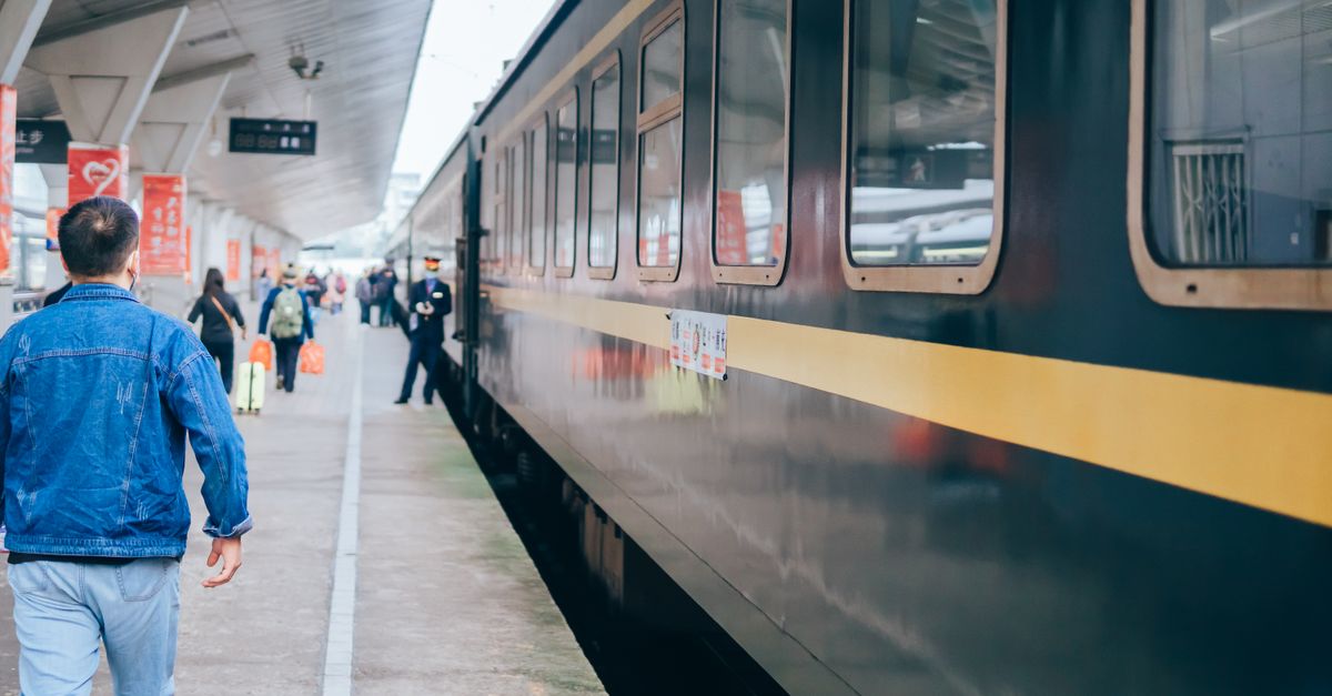 Passengers walking along a train at a busy station platform, capturing daily commuting vibes.