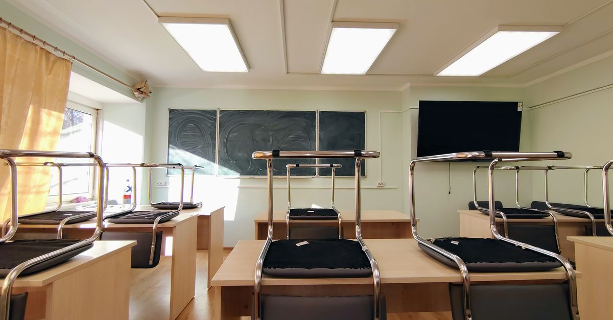 A wide view of an empty classroom with chairs stacked on desks and a blackboard in Moscow, Russia.