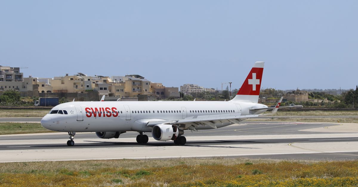 Swiss Airlines Airbus A321 taxiing on the runway under a clear blue sky.