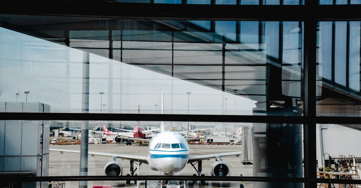 View of an airplane at Shanghai airport terminal, framed by modern architecture.