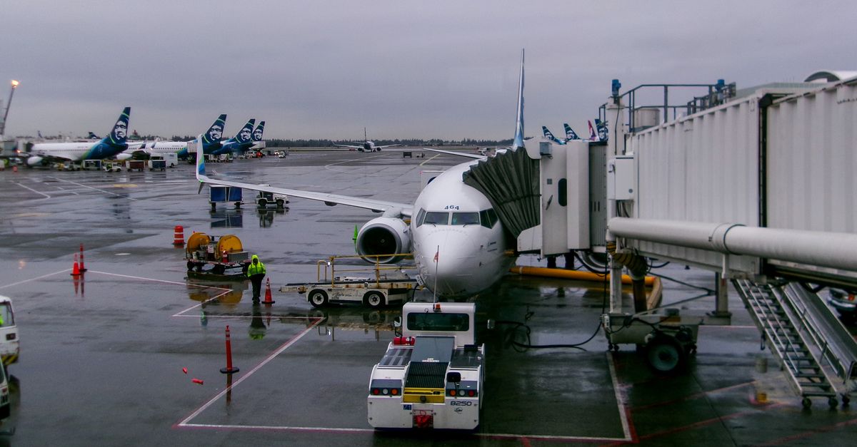 A passenger airplane docked at SeaTac Airport during a rainy day, showcasing airport operations.