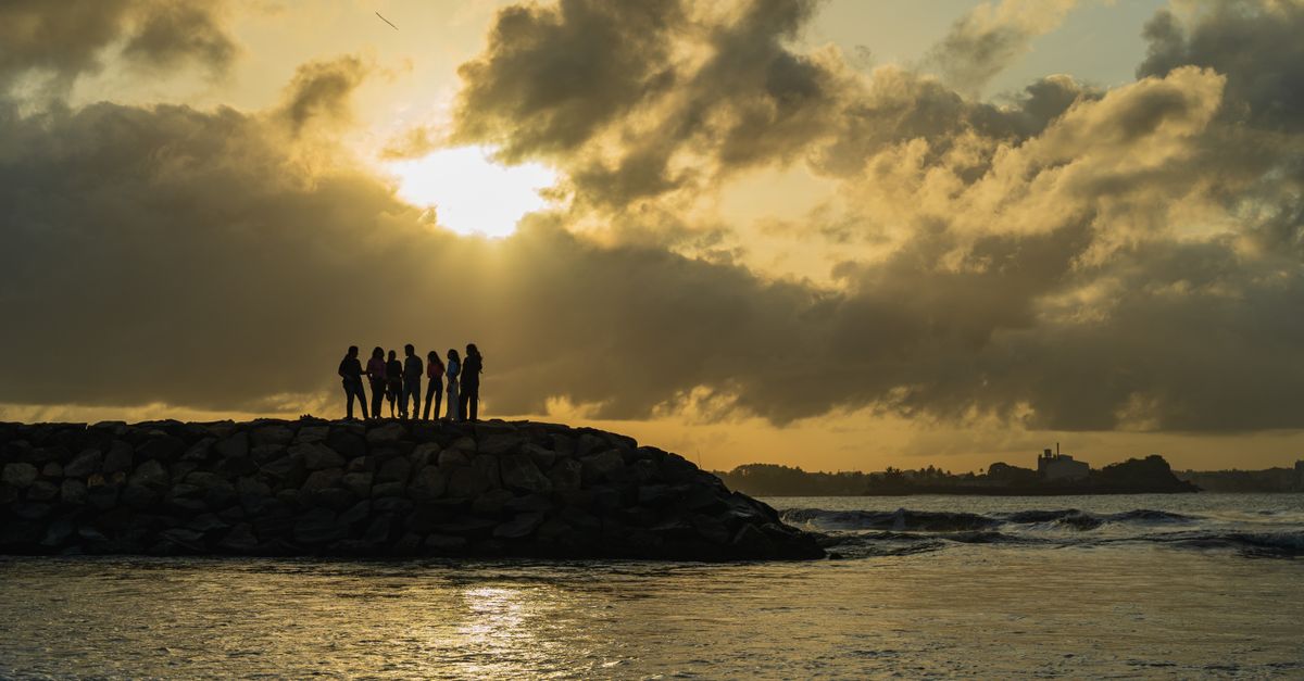 A group of people silhouetted against a stunning sunset at Galle Beach, Sri Lanka.