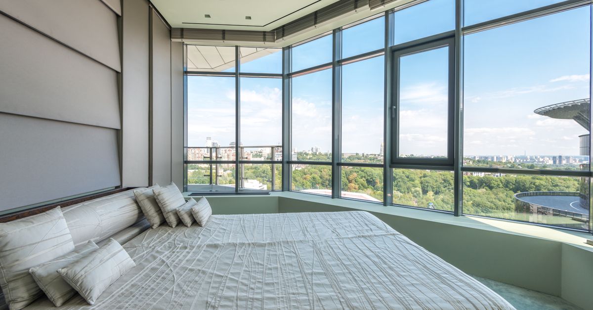 Luxurious bedroom featuring large windows and a panoramic city view.