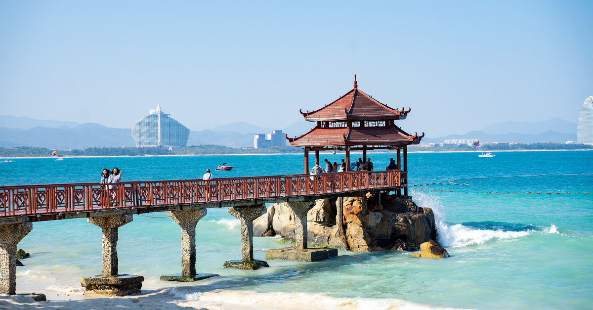 Idyllic view of a beach pier with a traditional pavilion against a clear blue sea and sky.