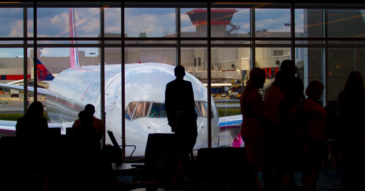 Silhouettes of travelers waiting at an airport terminal with an airplane visible through the window.