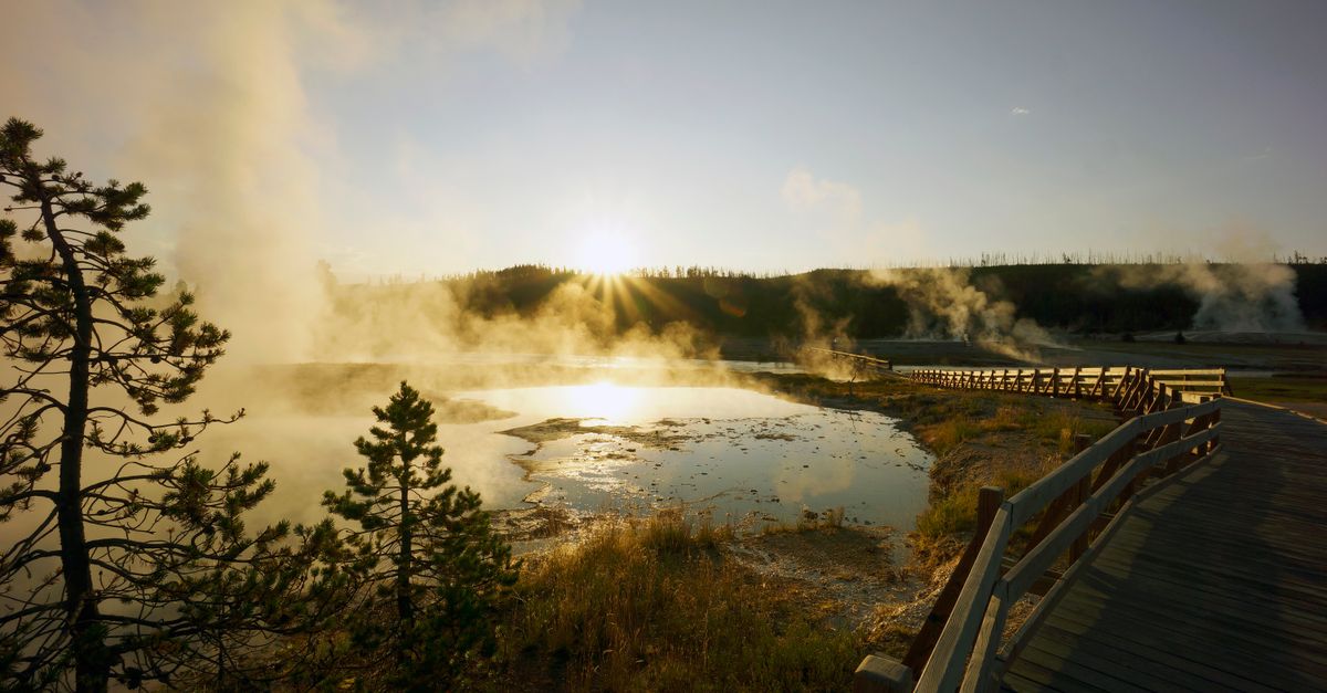 Breathtaking sunset view over a steaming geyser basin with boardwalk in Yellowstone National Park.