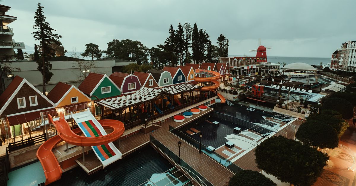 A vibrant resort in Antalya, Türkiye with colorful houses and exciting water slides overlooking the sea.